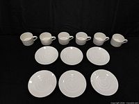 Five cups and eight saucers arranged on black backdrop