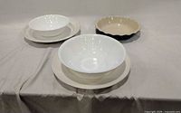 Group shot showing two Corelle bowls stacked on two white dinner plates and one Emile Henry scalloped pie dish