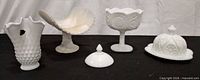 Group shot of all five milk glass pieces on black surface