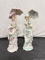 Front view of both porcelain figurines with parasols