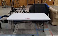 Front view of white plastic folding table with metal legs