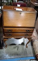 Front view of secretary desk showing drop front closed, two drawers, cabriole legs