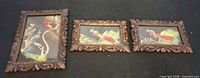 Front view of three carved wooden frames with bird prints