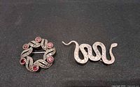 Front view of snake and wreath sterling brooches