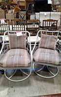 Pair of metal patio swivel chairs with cushions