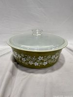 Side view of Pyrex olive green daisy round casserole with clear lid