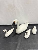 Group view of one large and three small wooden swan decoys