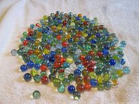 Loose pile of multicolored cat’s eye marbles spread on towel