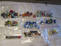 Overview of nine bags of marbles spread on towel