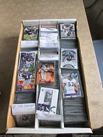 open long cardboard card storage box showing rows of sleeved Baltimore Ravens cards sorted by player