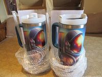 Front view of both boxed mugs showing astronaut graphics, bubble wrap and boxes