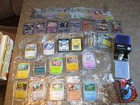 Wide view of entire lot: stacks of sleeved and unsleeved cards, holographic cards, code cards, storage box, sleeve packs