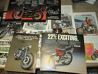 Group of loose motorcycle ad pages from 1970s Playboy magazine spread out on table