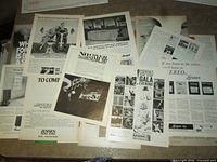 Group of loose 1970s Playboy magazine advertisement pages spread out on surface