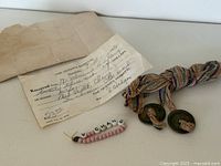All three items together: hospital receipt, bead bracelet, woven cord with coins