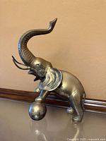 Full view of brass elephant balancing on ball