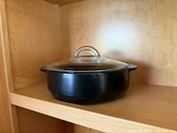 Side view of black Pampered Chef Rockcrok pot with lid on shelf