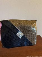 Front view of Whiting & Davis clutch showing black and gold mesh and silver accent
