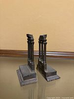Front angled view of both cast iron bookends showing columns and bases