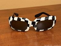 Front view of black and white checkerboard sunglasses on wood surface
