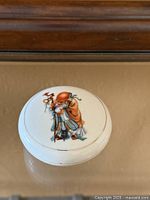 Top view of lidded porcelain box showing painted figure