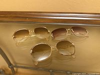 Three pairs of sunglasses displayed on glass surface