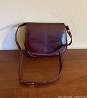 Front view of burgundy leather purse showing flap and strap
