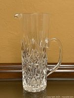 Front view of tall cut lead crystal pitcher with handle and spout