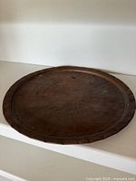 Top view of round hammered copper tray showing raised rim and surface wear