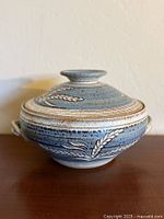 Side view of lidded stoneware pot showing glaze and handles