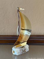 Front view of brass and copper sailboat on stone base with signature visible