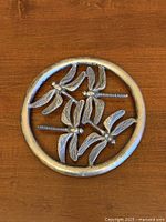 Top view of round dragonfly trivet on wood surface