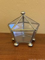 Front view closed trinket box showing pentagon shape, brass frame, ball feet