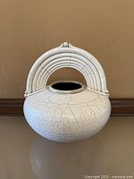 Front view of round white crackle vase with arched handle