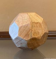 Overall view of wooden faceted sphere showing multiple facets and wood grain
