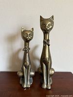 Front view of both brass cat figurines showing size difference and overall design