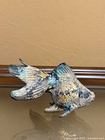 Left side view of painted cast metal goldfish showing color and texture