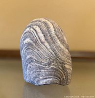 Front view showing curved grey and white stripes on stone