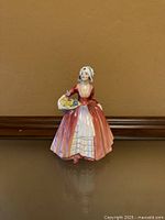 Front view of Royal Doulton Janet figurine with basket of flowers