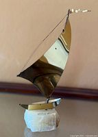 Front view of brass sailboat sculpture on stone base