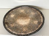 Top view of round silver tray showing full etched design and rim