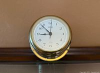 Front view of brass clock showing dial and hands
