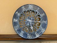 Front view showing verdigris metal wall clock with Roman numerals and scroll center