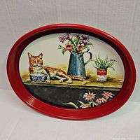 Front of oval metal tray showing cat and floral artwork