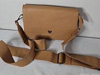 Front view of tan perforated Disney Mickey crossbody bag with strap visible