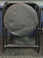 Front view of folded Outsunny stool showing round seat and steel frame