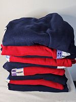 Stack of six navy and red Jerzees sweaters with size tags visible