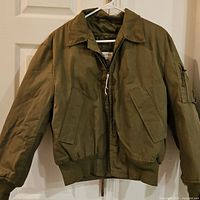 Full front view of olive drab military cold weather jacket on hanger