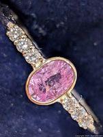 Close-up of ring showing oval pink sapphire and lab diamond accents