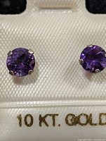 Front view of amethyst stud earrings on card